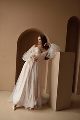 Portrait of a young beautiful bride in full growth. Girl posing in a room near the window.