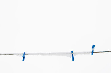 winter background: clothesline covered with snow, several blue clothespins, selective focus