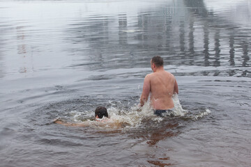 Bathing people in  the icy water of a winter river in water baptism in the Orthodox tradition. Dnieper. Kiev. Ukraine