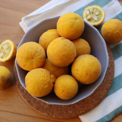 Trifoliate yellow fruits on wooden table. Many Poncirus trifoliata fruits in a bowl