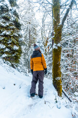 A young woman with a yellow jacket in the snowy forest of the Artikutza natural park in oiartzun...