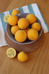 Trifoliate yellow fruits on wooden table. Many Poncirus trifoliata fruits in a bowl