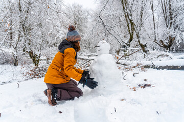 A young Caucasian woman making a snowman in the snowy forest of the Artikutza natural park in...