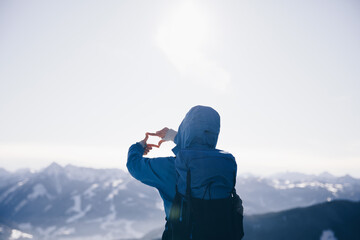 Wandernde Person bildet Rahmen mit Händen und genießt die Aussicht auf die schneebedeckten Berge...