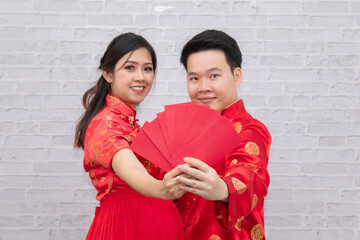 Obraz na płótnie Canvas Selective focus young Asian couple newlywed hug together show red envelops angpao in Traditional Chinese New Year Festival Holiday, Happy family pregnancy lucky woman expectation to give birth for boy