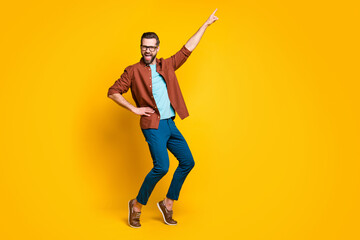 Fototapeta na wymiar Full size photo of funky crazy young man dancer hold hand waist point finger up isolated on vivid yellow color background