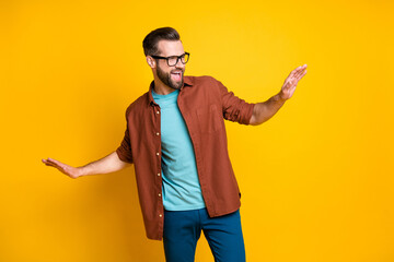 Photo of charming funky optimistic young man raise hands look dance free-time isolated on yellow color background