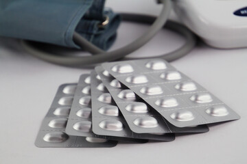 Selective focus on medical pills against hypertension and a modern blood pressure monitor in the...