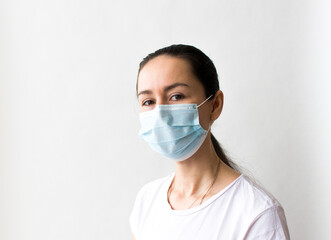 Head and shoulders portrait of female doctor wearing protective mask and looking at camera posing against white background, copy space