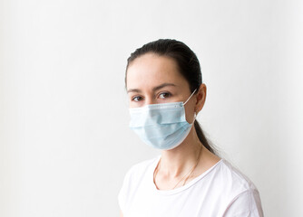 Head and shoulders portrait of female doctor wearing protective mask and looking at camera posing against white background, copy space
