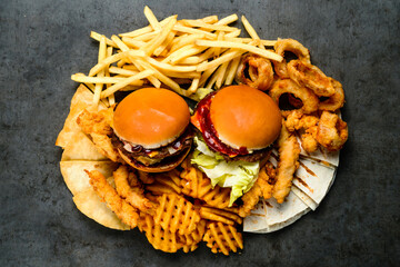 Combined set of fast food. Juicy delicious hamburger, French fries, chicken legs and sauce on a black background. Fast food restaurant. Food delivery. large set of fast food burgers fries and snacks