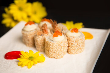 Close up of sushi roll Ebi Tempura with shrimp served with red caviar on top. Yellow camomile...