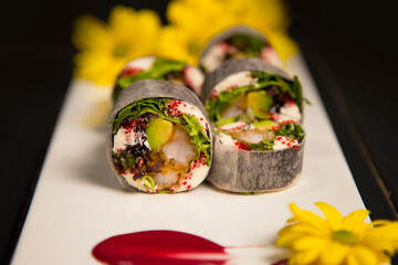 Macro of healthy Japanese rice free sushi roll with tempura shrimp wrapped in daikon radish. Yellow...
