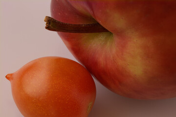 an apple with a cherry tomato