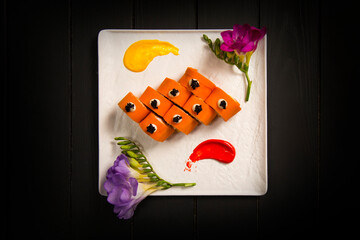 Directly above of Japanese no rice sushi roll wrapped in carrot daikon served with black tobiko...