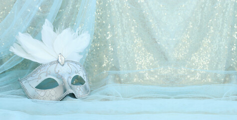 Obraz premium Photo of elegant and delicate white Venetian mask over gold and blue chiffon background