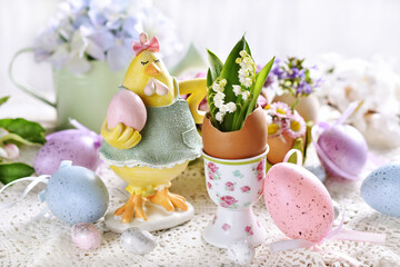 Obraz na płótnie Canvas Easter decoration with a hen figurine and spring flowers in egg shells
