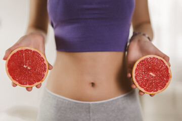 Young woman in fitness clothing holding grapefruits. Concept of healthy eating.