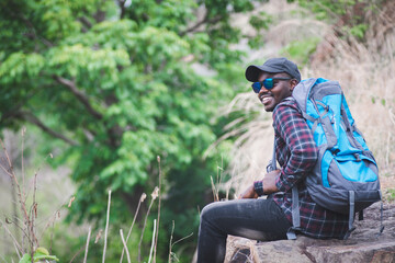 African man traveler sitting on the top of moutain with backpack