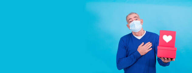 Valentine's Day during the coronavirus pandemic concept. attractive man with surgical mask and gift. Covid-19 lifestyle