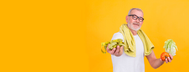 attractive mature man with tape measure in one hand and lettuce and tomato in the other, diet and health concept
