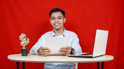 Asian business man with laptop and many paper isolated red background