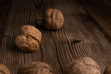 Photography of walnut on the brown wooden desk. Focus on the middle nut and soft focus on foreground.