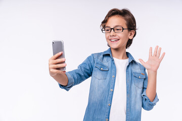 Funny smiling male kid having video call on phone isolated over white background