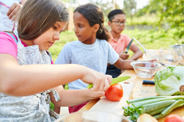Children at the summer camp cooking class prepare salad