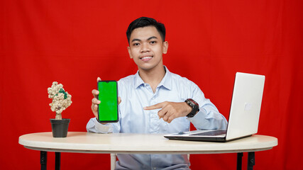 Young asian business man pointing handphone green screen isolated red background