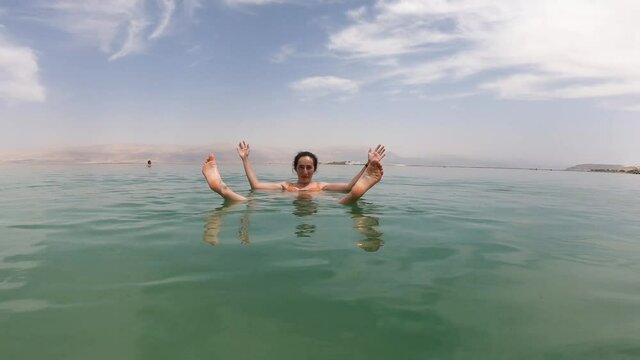 Beautiful girl floating on the salty waters of the Dead Sea, Israel
