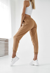 fit woman standing in light beige pants and white shirt