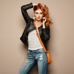 Fashion portrait of beautiful young woman with red hair. Girl in blouse and jeans. Jewelry and...