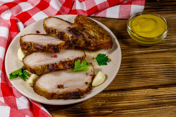 Baked pork belly in a plate on wooden table