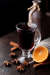 Hot autumn grog in a glass with honey and spices, ingredients around, laying on a wooden background