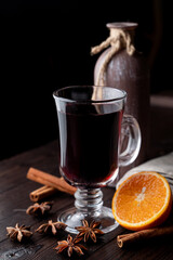 Hot autumn grog in a glass with honey and spices, ingredients around, laying on a wooden background