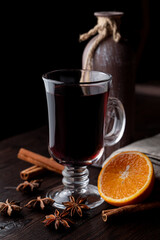 Hot autumn grog in a glass with honey and spices, ingredients around, laying on a wooden background