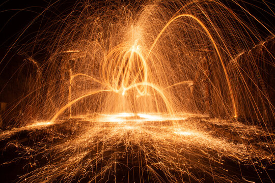 Long exposure night photography of flame trails and sparks from burning steel wool - Powered by Adobe