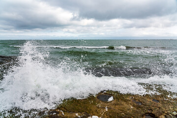 Wave splashing at the rocks, freshness on beach