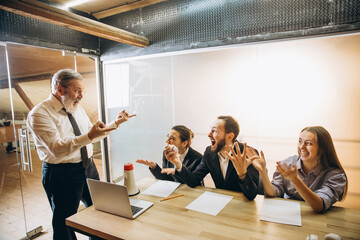 Scary. Angry boss with megaphone screaming at employees in office, scared and annoyed colleagues listening at the table stressed out. Funny meeting, business, office concept. Screaming mad.