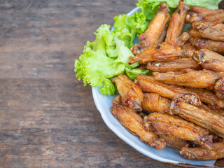 Fried chicken wings with fish sauce with salad vegetables on a white plate placed on a wooden table. Close-up photo. Space for text. Concept of foods