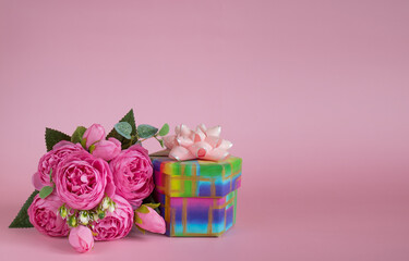 Gift box and bouquet of flowers on pink background. The concept of congratulations for Mother's Day, Valentine's Day, birthday, International Women's day and other holidays. Copy space