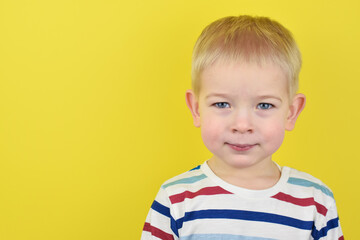 Happy smiling little boy on color background. Portrait of beautiful European boy two years old on a yellow background. Copy space for text.