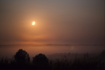 The moon shines in the fog at night. Natural background.