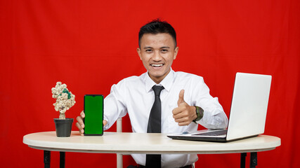 Young asian business man pointing handphone green screen isolated red background