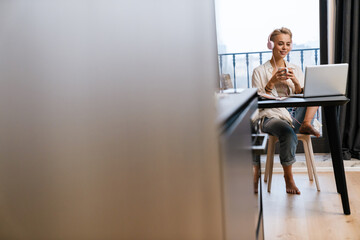 Lovely young woman studying online while sitting