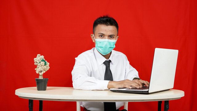 Asian business man wearing mask with laptop isolated red background