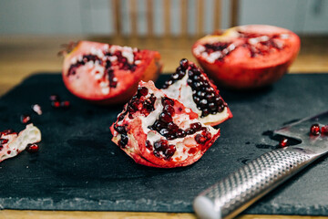 Pomegranate on a slate cut open with a knife with its seeds on display