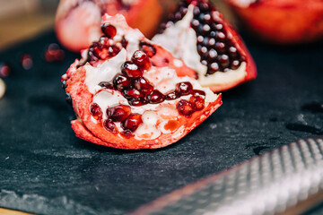 Pomegranate on a slate cut open with a knife with its seeds on display