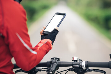 Cyclist use smartphone when riding mountain bike on forest trail
